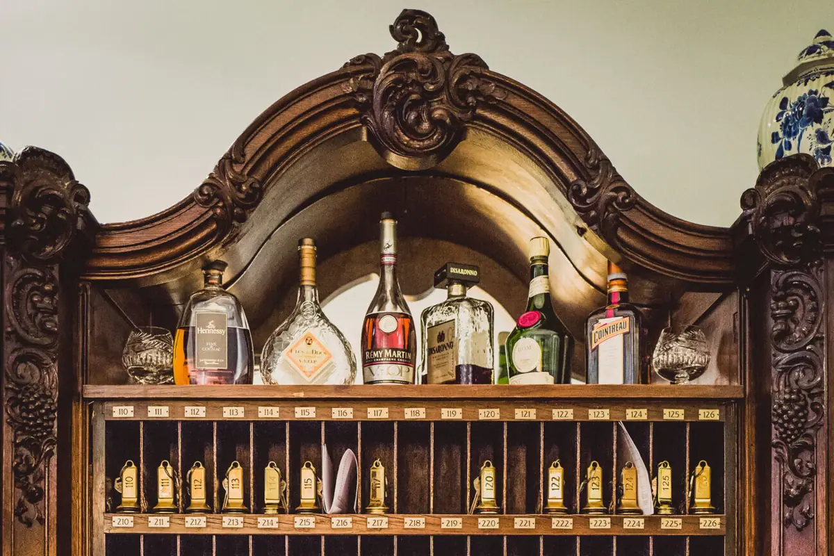 Wooden shelf with hotel room keys and bottles of alcohol