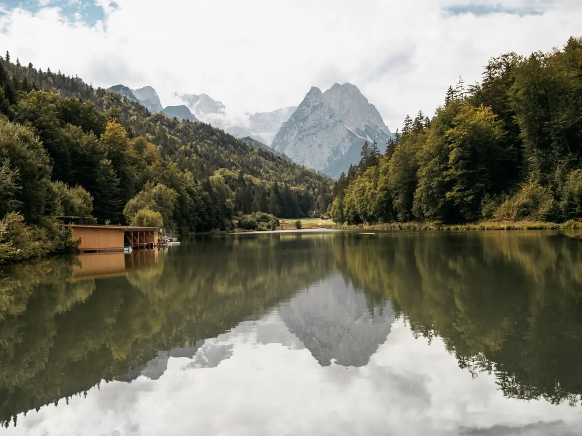 A lake with a hut and mountains in the background.