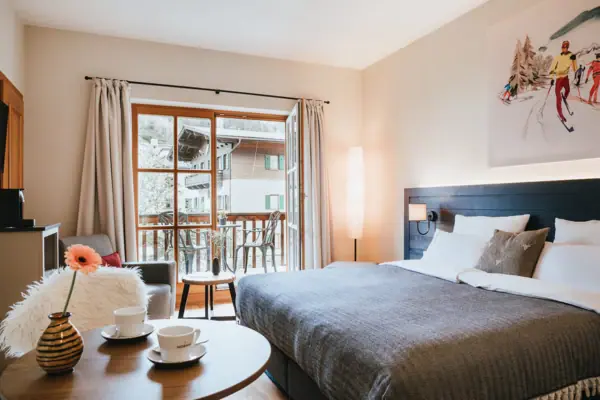 A hotel room at the HENRI Hotel Kitzbühel with a bed, a sofa and a table.