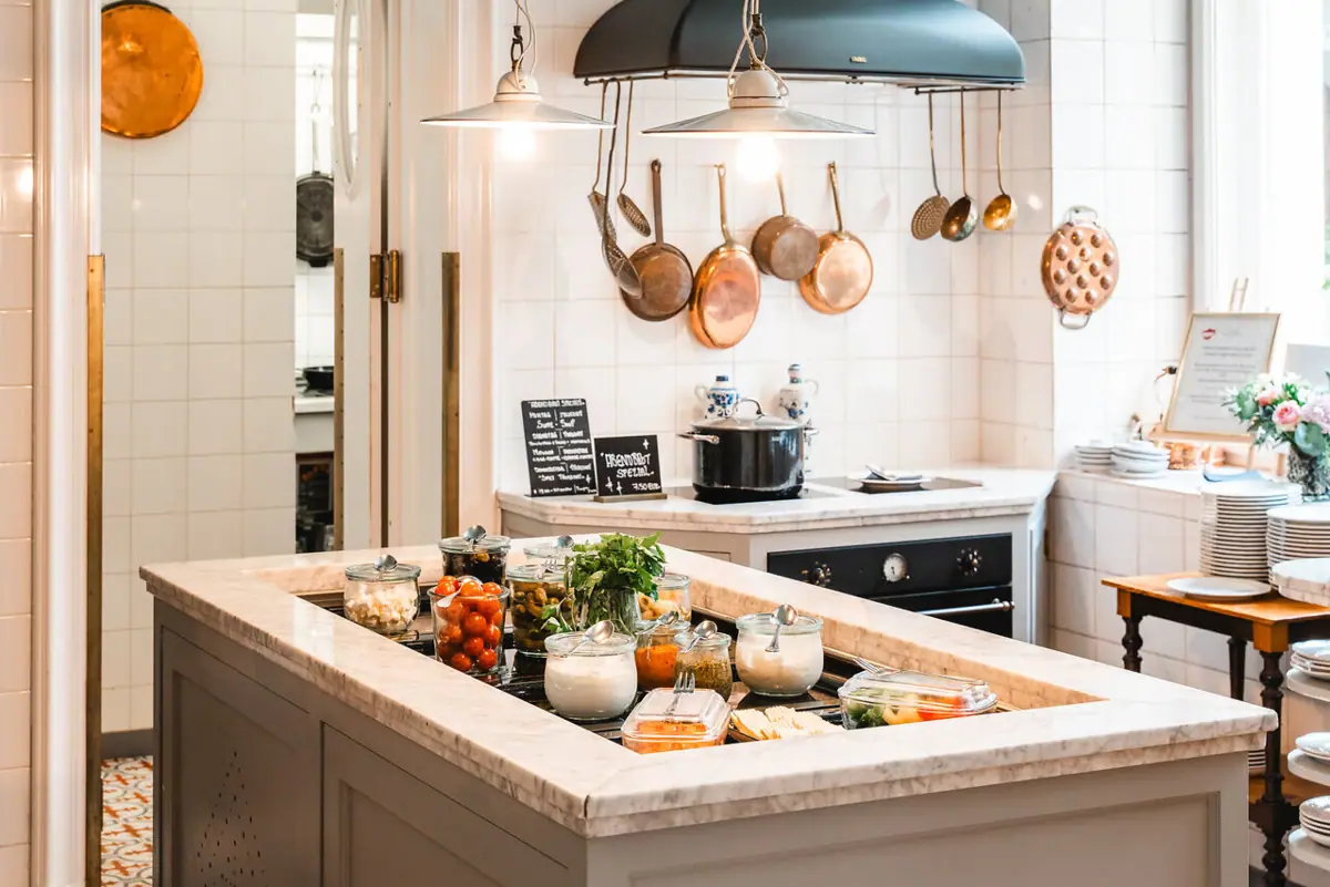 A kitchen with a large island on which food is placed.