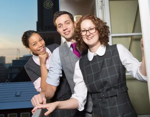 A group of people are standing in front of a window.