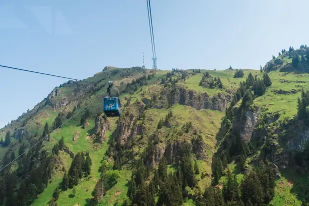 Cable car in front of a green mountain slope