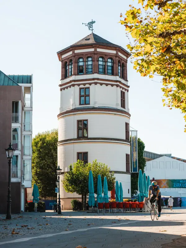 A man is cycling past a round building.