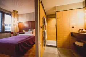 The S-Studio in the HENRI Hotel Düsseldorf with a bed and an adjoining bathroom with a washbasin and shower.