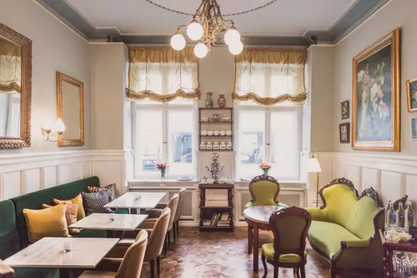 HENRI Hotel Berlin: Classic Salon Interiors A bright, classically designed lounge at HENRI Berlin, featuring green velvet sofas, marble tables, an antique samovar and stately oil paintings on the walls.