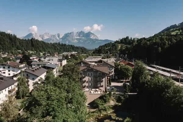 The HENRI Hotel Kitzbühel, with trees and mountains in the background.