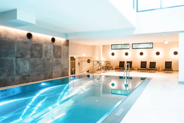 Wellness area at the HENRI Hotel Kitzbühel, featuring an indoor pool and chairs.