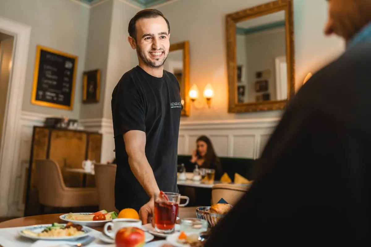 A man smiles at a table with food.