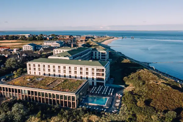 A building with a pool and a beach in the background.