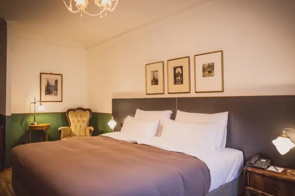 A bed with a chandelier and pictures on the wall.