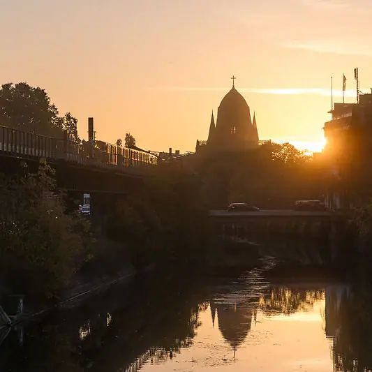 Bridge over a river with a building in the background at sunset.