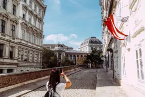 A woman photographing a building outdoors.