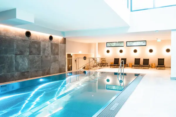 HENRI Kitzbühel Pool Indoor pool with steps and chairs.
