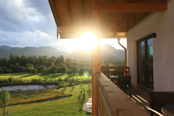 Sun shining through the trees onto a veranda balcony at aja Riuhpolding.