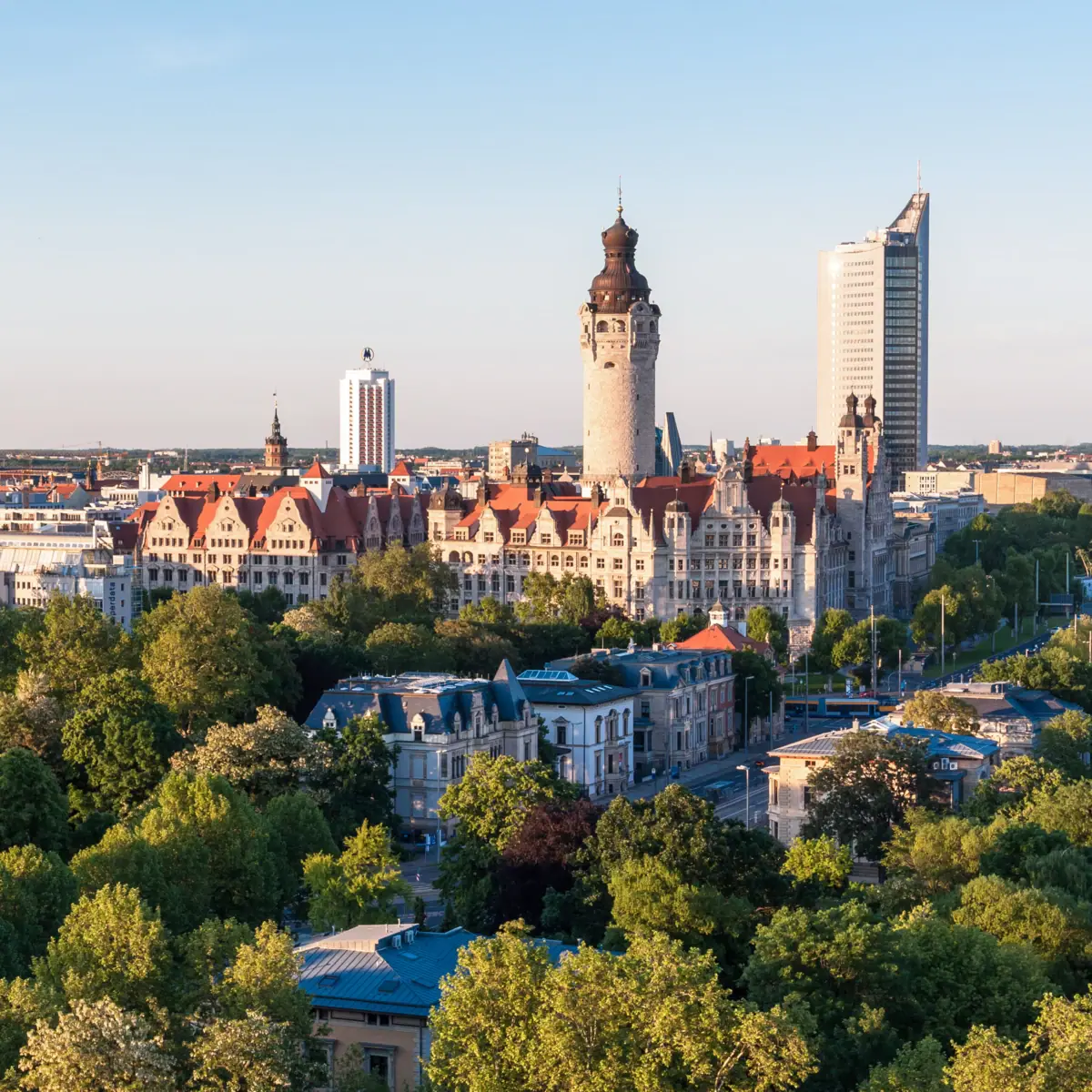 The Leipzig skyline with trees and buildings in the morning light.