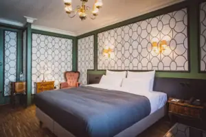 A bed with a chair and a chandelier.