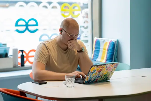 A man sits at a table and supports his face with his hand.
