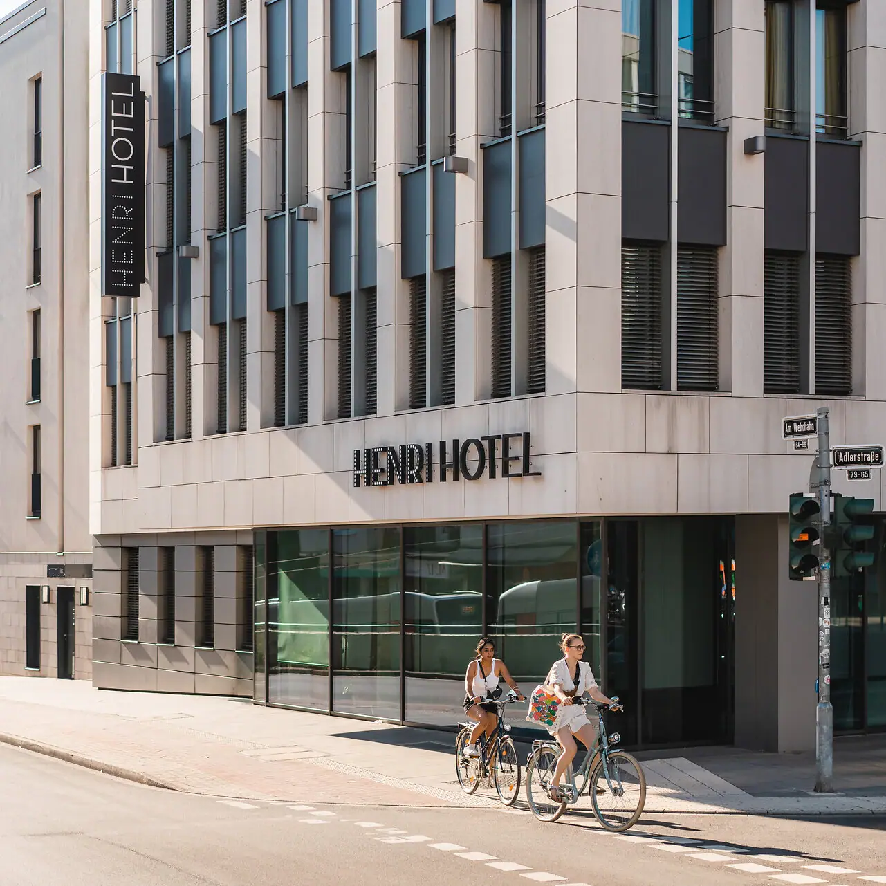 A group of people riding bicycles in front of a hotel.
