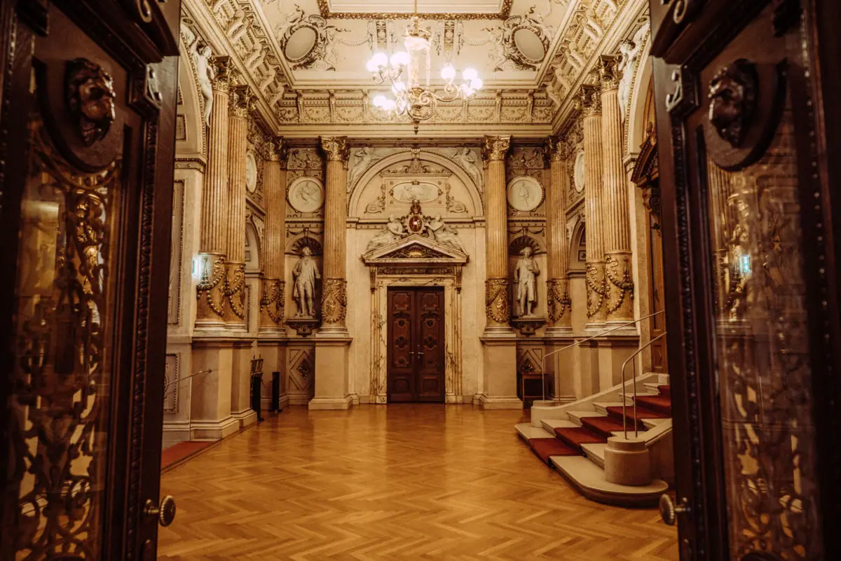 Large, richly decorated room with staircase and chandelier in Napoleon III style.
