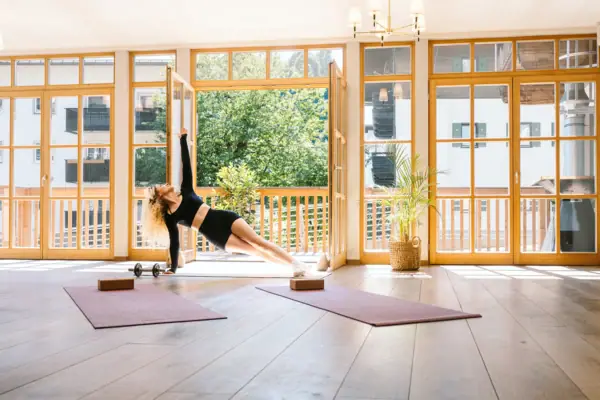 A woman does a plank exercise in a room with windows.