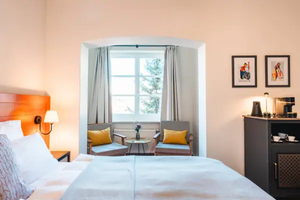 A bedroom with a bed and chairs.