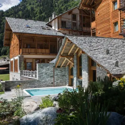 A hotel with a pool in the foreground and mountains in the background.