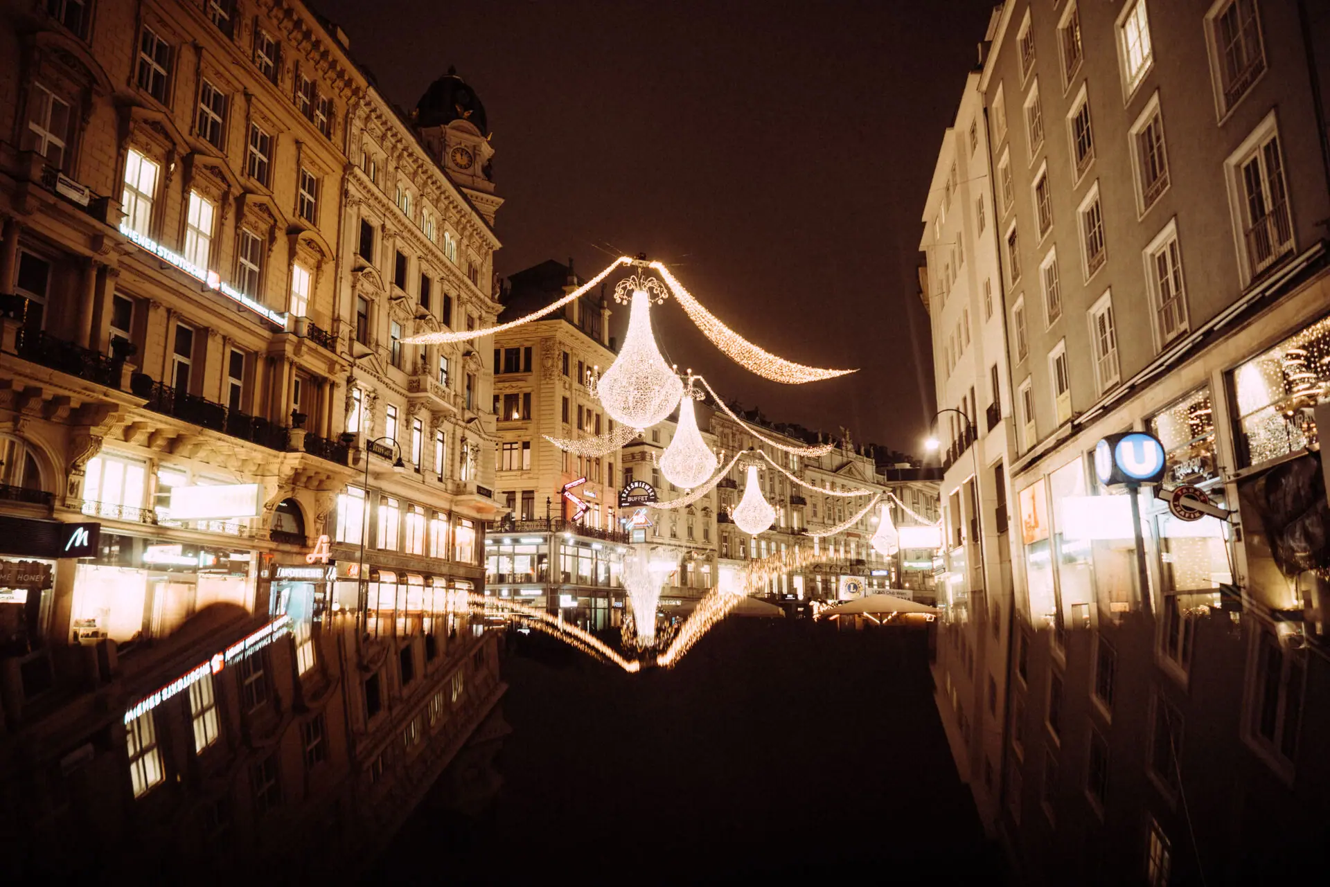 A street with illuminated buildings at night.