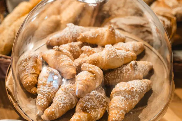 A plate of croissants dusted with icing sugar.