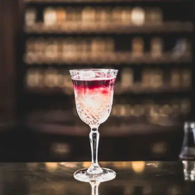 A glass with a drink on a bar.