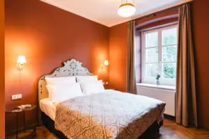 A room with a bed and a window with a view of the countryside