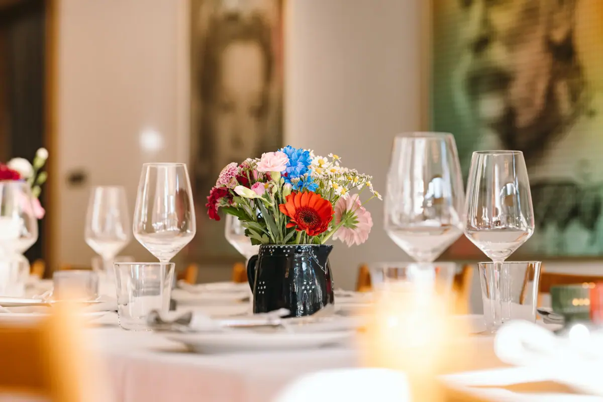 A table with glasses and a vase of flowers.