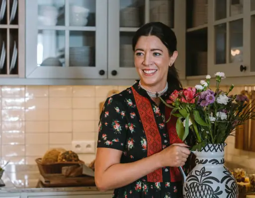 A woman holds a vase of flowers.