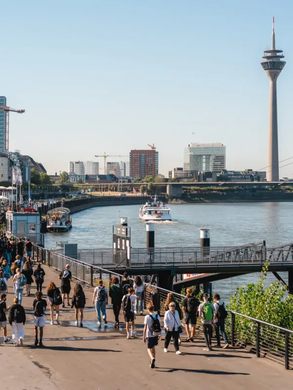 A group of people are walking along a path near the water.