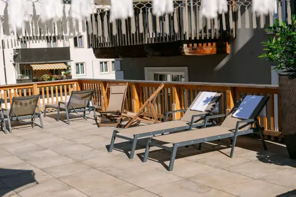 A terrace with chairs and a white parasol.