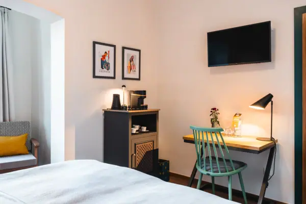 A room with a bed, desk and television.