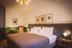 A bed with a chandelier and pictures on the wall.