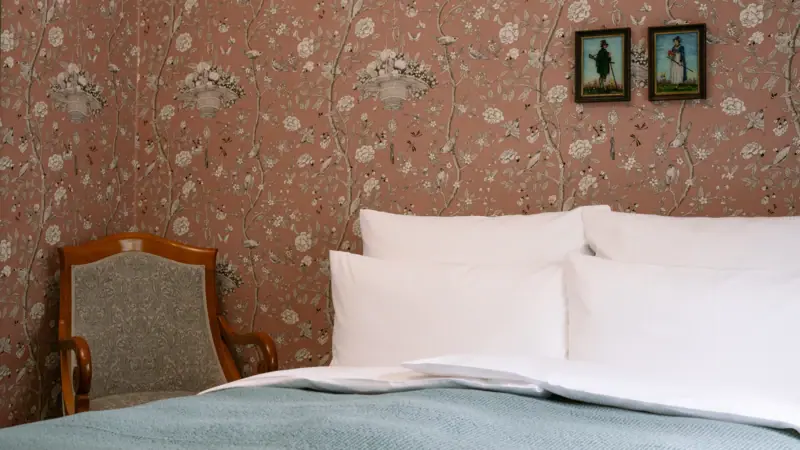 A bed with neatly arranged pillows and a chair in a well-designed room.