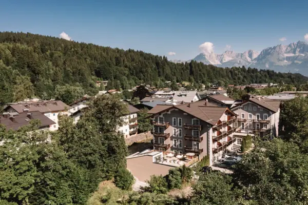 A group of buildings with trees and mountains in the background.