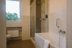 Bathroom with shower and bath, fitted with modern fittings and a mirror.