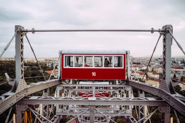 Red and white ferris wheel against a cloudy sky.