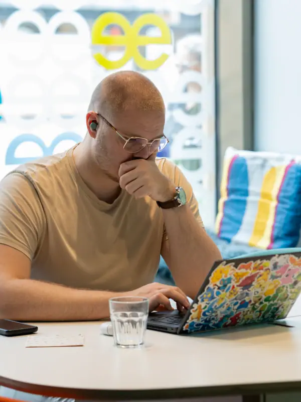 A man sits at a table and supports his face with his hand.