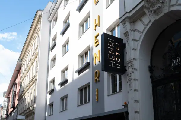 Sign on a building facade with windows and a cloudy sky in the background.