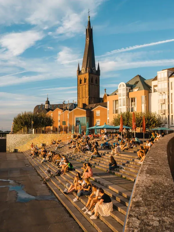 A group of people are sitting on the steps in front of a building.