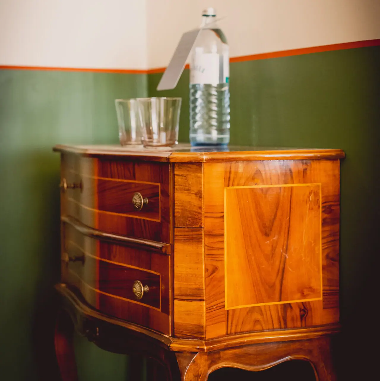 Wooden chest of drawers with a water bottle on it