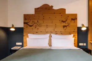 A bed with a wooden headboard and white bed linen in a hotel room