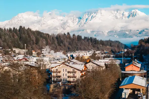 HENRI Kitzbühel drone view A mountain village with snow-capped mountains in the background.