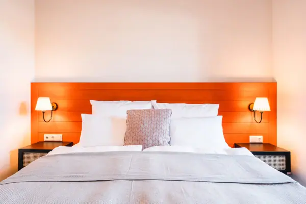 A bed with pillows and a lamp on the bedside table.