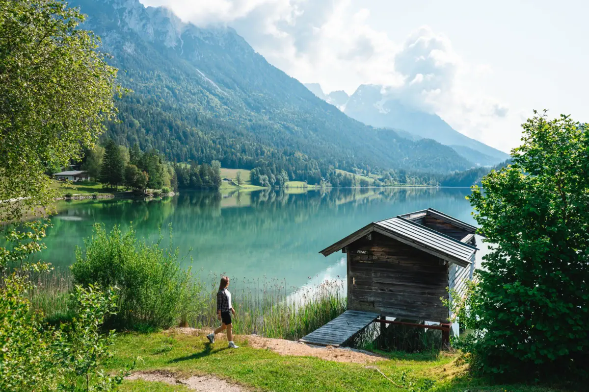 A person is walking on the grass beside a lake.