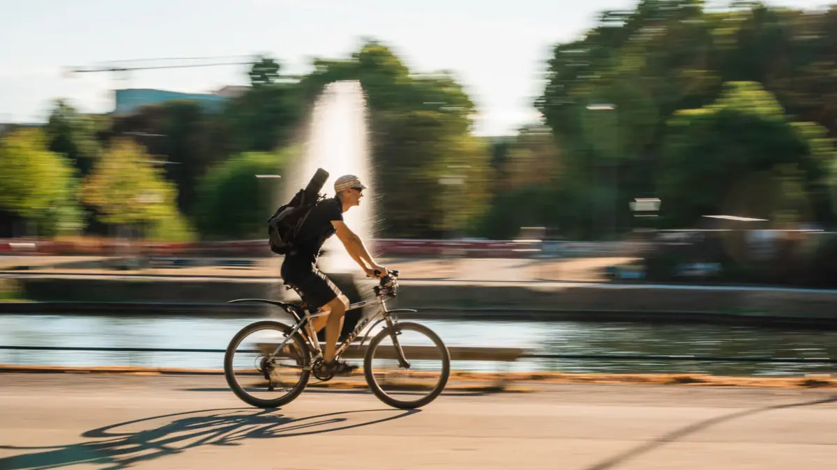 A man is riding a bicycle with a rucksack.