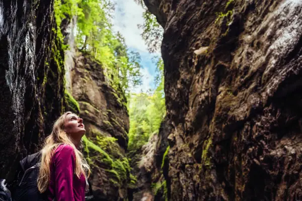 A woman looks up in a gorge.